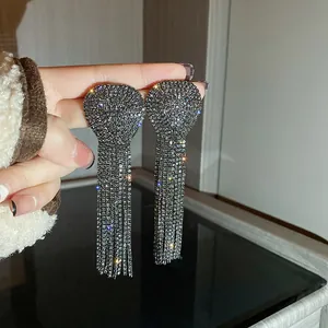 Close-up of glamorous oversized full rhinestone tassel earrings for evening wear.