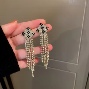 Detailed view of glamorous full rhinestone tassel earrings with a chic checkered diamond top.