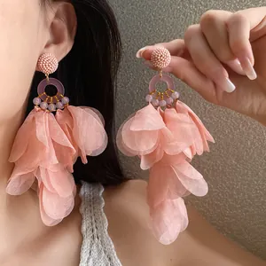 Dettaglio orecchini a nappa con petali rosa e perline indossati dal modello