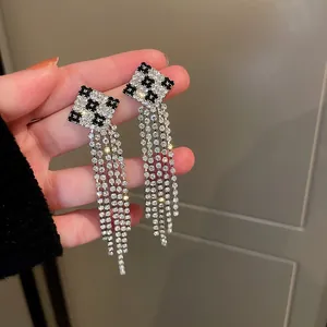 Detailed macro view of long rhinestone tassel earrings with black and white checkerboard tops