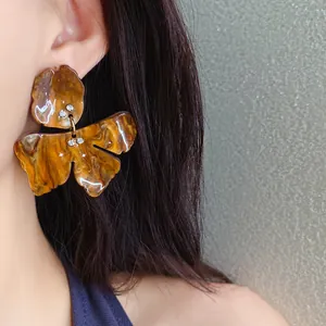 Close-up view of vintage brown resin flower earrings with rhinestones on a model