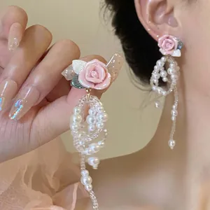 Close-up of elegant pink rose and pearl bead dangle earrings worn by an Asian model.