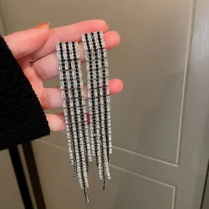 Detail view of long tassel earrings with sparkling black and white rhinestones for parties.