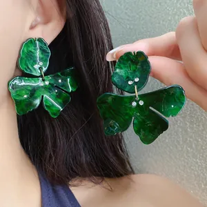 Detailed view of dark green resin flower earrings with sparkling crystal accents