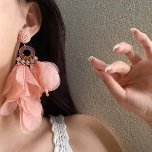 Primo piano di orecchini con nappe a petali rosa indossati da una modella per lo stile.