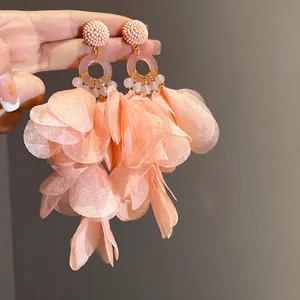 Primo piano di orecchini a nappa con petali in tessuto rosa per un look da vacanza