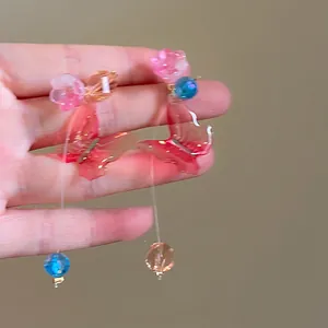 Detailed view of colorful glass butterfly earrings with floral accents and silver needles.