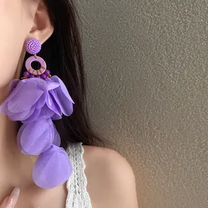 Dettaglio ravvicinato di orecchini a nappa con petali in tessuto viola vivace