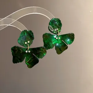 Detail view showing the marble texture of green resin flower earrings with rhinestones