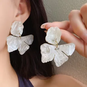 Close-up of elegant resin flower earrings with delicate rhinestone accents and pearly finish