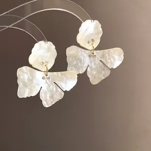 Detail view of pearlized resin flower earrings with crystal accents and silver needles.