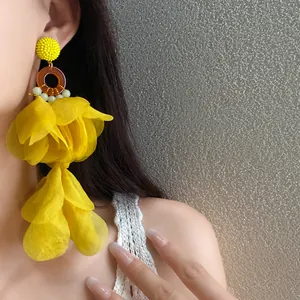 Dettaglio di orecchini a nappa con petali in tessuto giallo brillante sulla modella