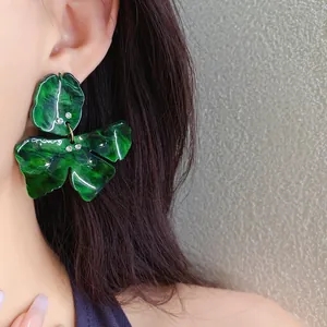 Detail of green resin flower earrings with marble pattern and crystal accents on model
