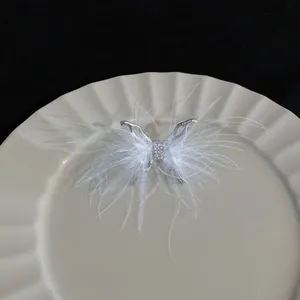 Detalle de un elegante anillo abierto de mariposa con plumas blancas y cristales brillantes