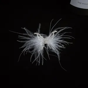 Detalle de un anillo de mariposa con plumas blancas y brillantes sobre fondo negro.