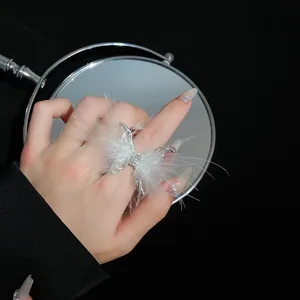 Detalle de un elegante anillo de mariposa ajustable con plumas blancas y cristales