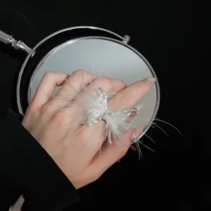 Primer plano de un anillo de mariposa plateado decorado con elegantes plumas blancas
