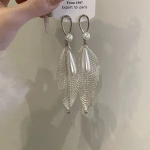 Detalle de pendientes de malla plateada con elegantes perlas redondas y de lágrima.