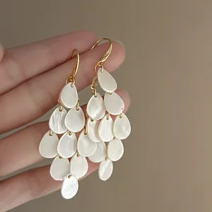 Detailed macro view of French vintage pearly teardrop tassel earrings with gold hooks
