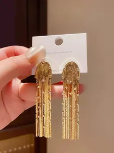 Detailed view of gold fringe tassel earrings with sparkling rhinestones on a card.