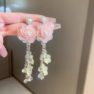Primer plano detallado de pendientes de rosa de tela rosa con borlas de cristal y perlas