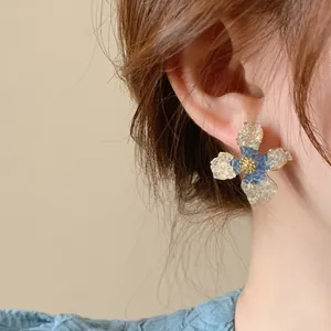 Close-up of colorblock crystal flower earrings worn on the ear, showing delicate detail.