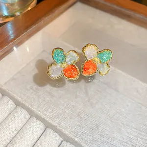 Detailed macro shot of multicolor crystal flower stud earrings featuring elegant gold borders