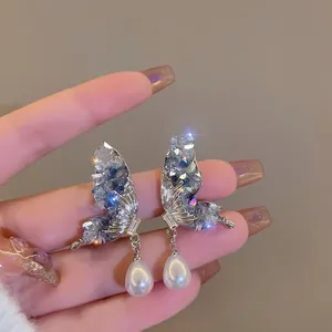 Detailed view of elegant silver butterfly stud earrings with blue crystals and drop pearls