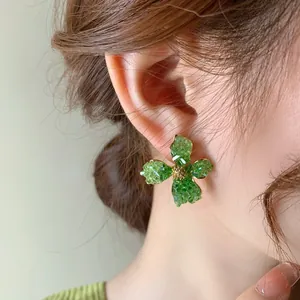 Close-up of these elegant green crushed crystal flower earrings on a model's ear
