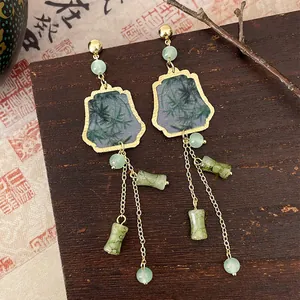 Close-up of Chinese style bamboo ink wash earrings with green beads on wooden background