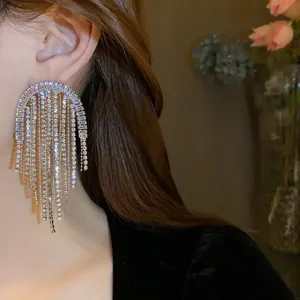 Dettaglio di orecchini a goccia con nappine di strass su modella per un look di lusso
