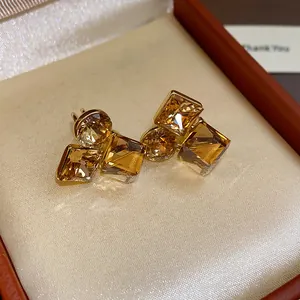 Vue détaillée des clips d'oreilles carrés en cristal champagne dans un écrin rouge