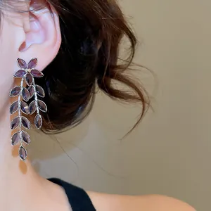 Detailed close-up of purple zircon flower and leaf tassel earrings worn on a model's ear