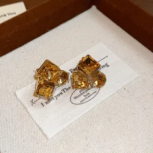 Gros plan de boucles d'oreilles en cristal ambre carré avec une finition dorée luxe
