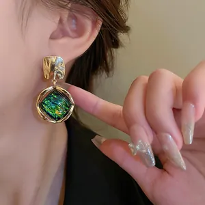 Primer plano de pendientes vintage con resina verde y acabado dorado