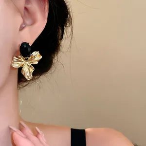 Elegant vintage gold-tone flower statement earrings featuring a large oval black gemstone on ear