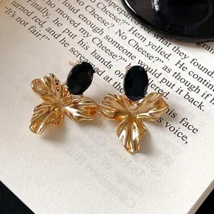 Vintage gold-toned flower earrings featuring oval black stones set on a classic book page