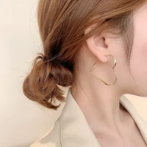 Detailed view of oversized gold heart hoop earrings worn on a model's ear for style