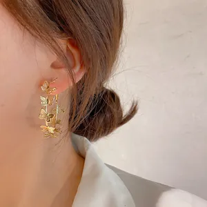 Close-up of gold butterfly hoop earrings worn on a model's ear