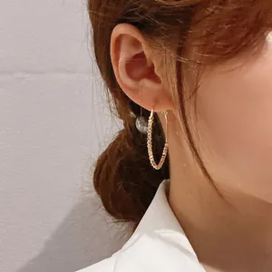 Detailed macro view of stylish gold beaded geometric hoop earrings worn by a model