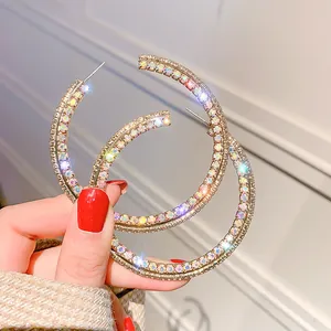Macro detail of oversized gold hoop earrings featuring multi-row iridescent sparkling crystals