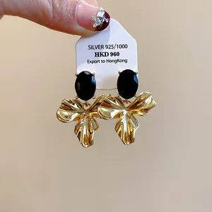 Close-up of vintage flower earrings with black oval stones and 925 silver tag.