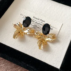 Macro view of vintage gold flower earrings featuring black oval gemstones on velvet.