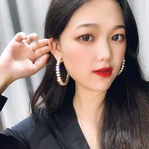 Detailed view of oversized sparkling crystal hoop earrings on Asian female model