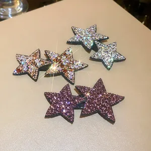 Close-up detail of sparkly Y2K star hair clips with rhinestones in golden, silver, and purple.
