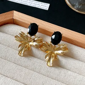 Close-up of vintage gold flower earrings featuring a textured black oval gemstone inlay