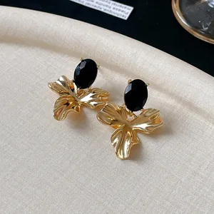 Detail of vintage gold flower earrings with oval black stones and textured metal