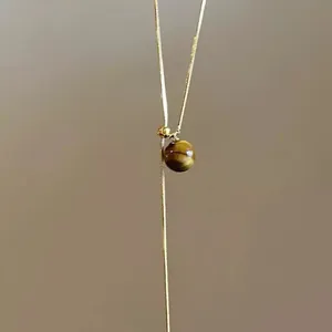 Close-up of 14K gold-plated snake chain necklace featuring a polished tiger eye stone