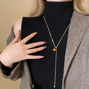 Detail of 14K gold plated necklace with tiger eye stone on a model.