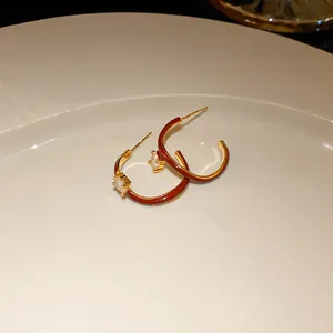 Detailed macro view of dark red enamel hoop earrings featuring a sparkling zircon stone